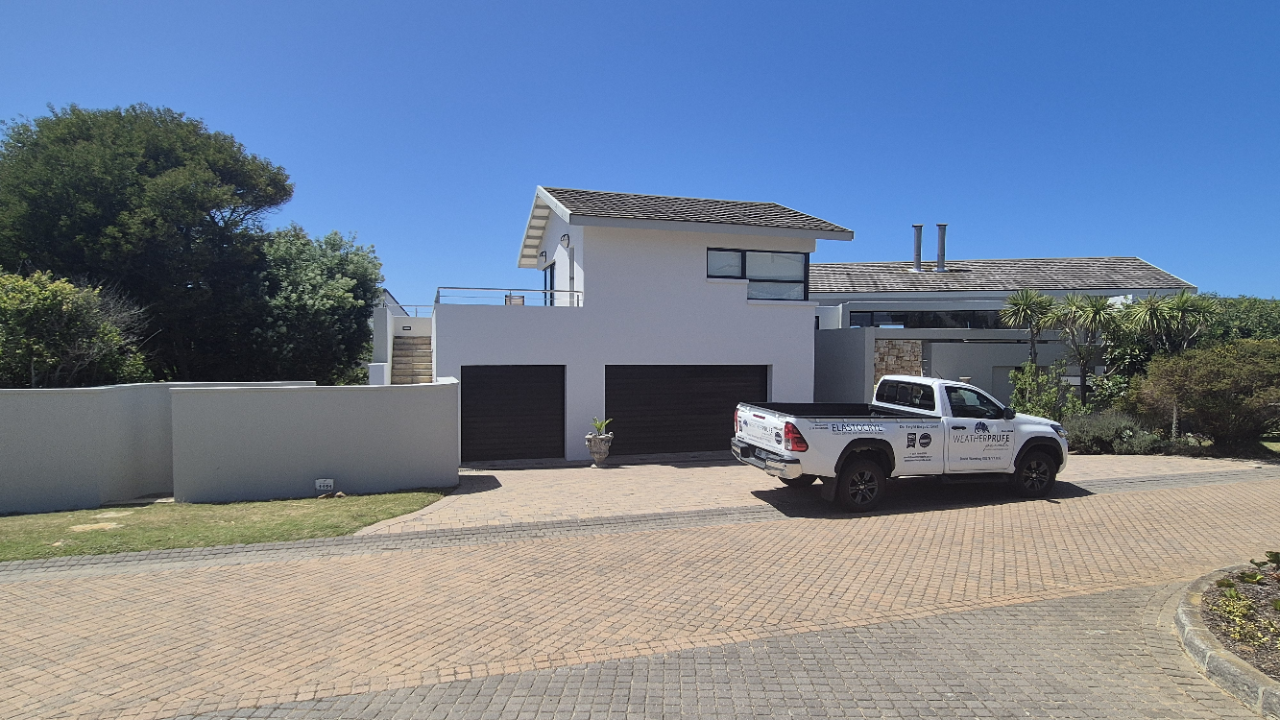 Technician filling visible wall cracks with Weatherbond Enhance and cement mixture to reinforce surfaces before painting.